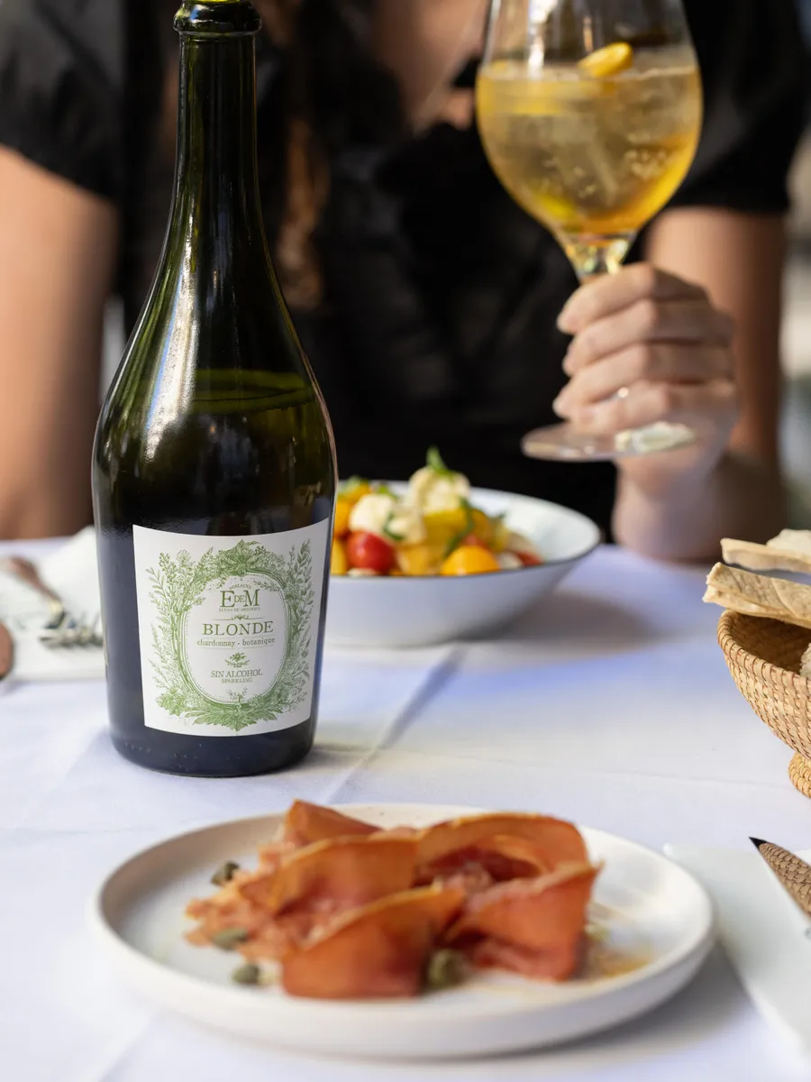 Bottle of BLONDE with a cocktail glass and small dishes on the table