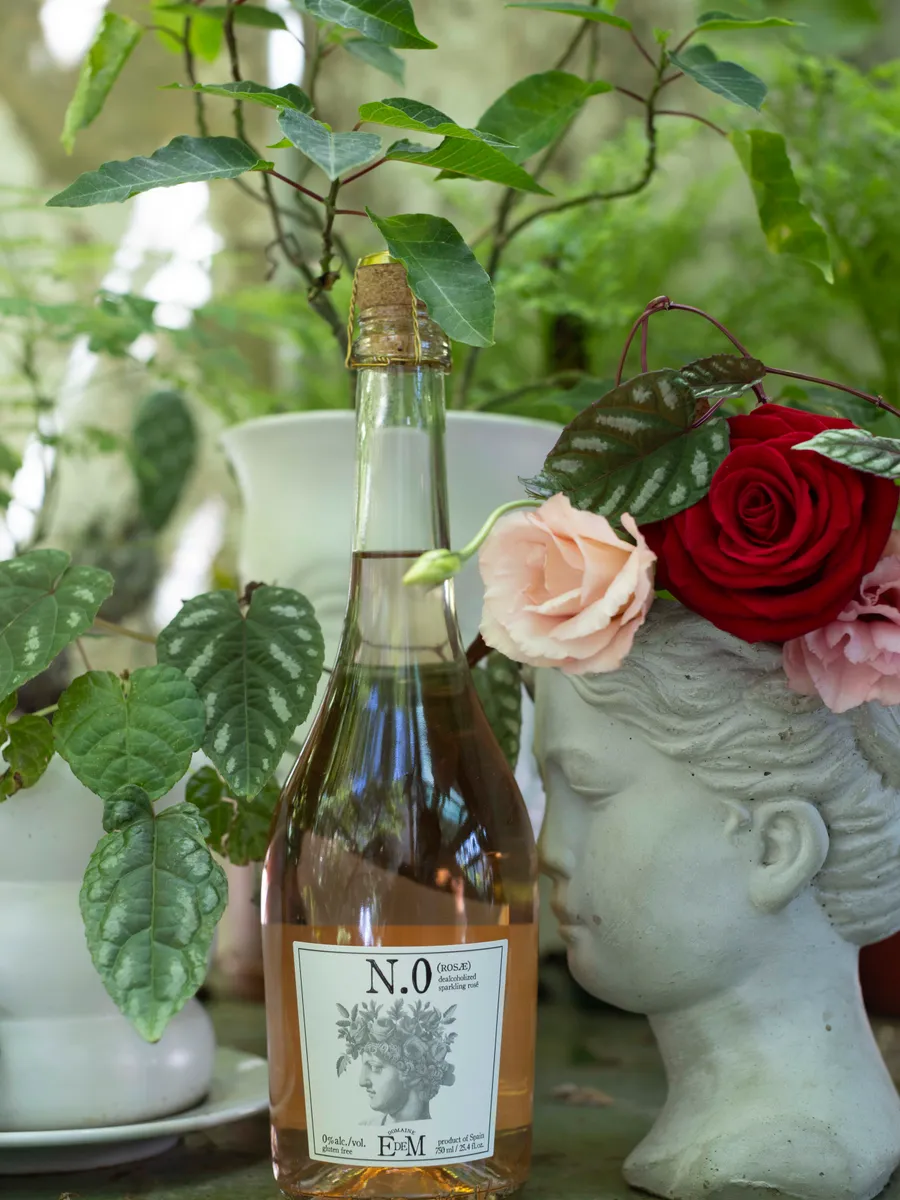Bottle of ROSAE next to roses and a classical bust